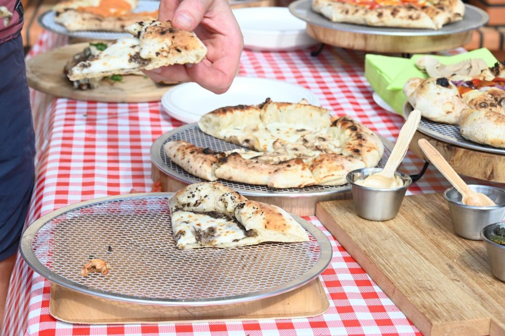 אורחים מצלמים את הפיצות על השולחן עם המטבלים